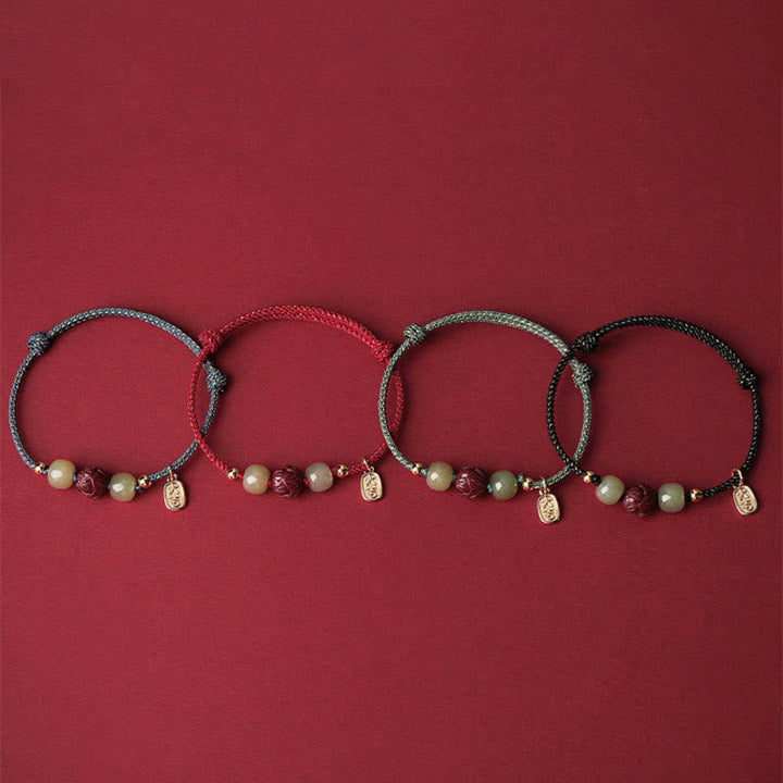 Vier Armbänder mit Perlen und Lotus-Anhängern auf rotem Hintergrund.