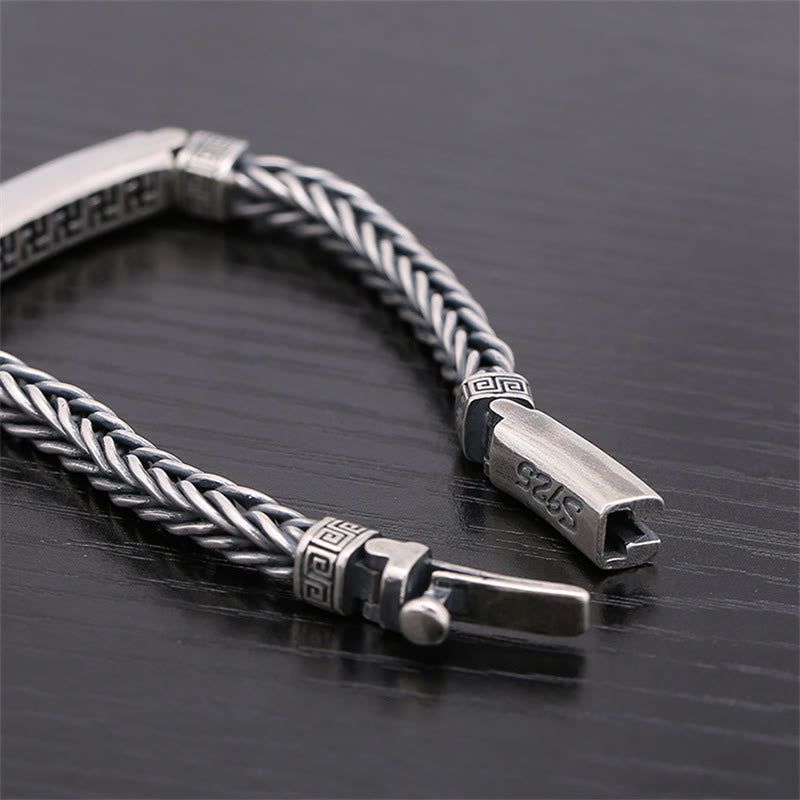 Silbernes geflochtenes Armband mit geometrischen Verzierungen auf dunklem Hintergrund