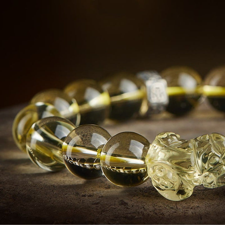 Armband Tigerauge Citrin Pixiu mit glänzenden Perlen auf Naturstein Oberfläche