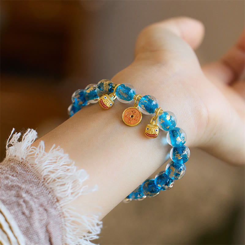 Blaues Armband mit Kupfer-Anhängern am Handgelenk getragen elegant.