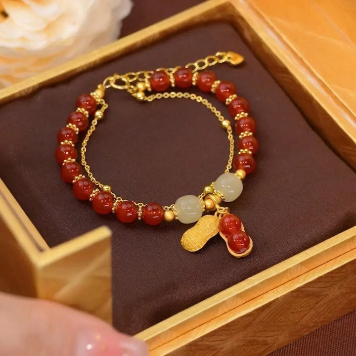 Rotes Jade Armband mit goldenen Elementen und Glücksanhänger.