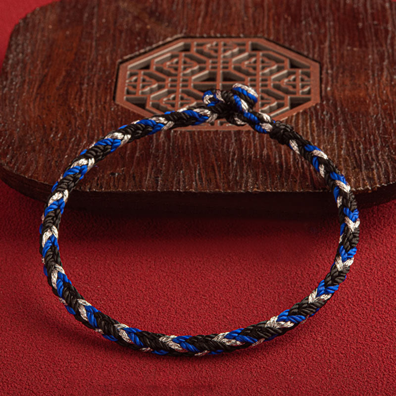 Mehrfarbiges Glücksband Armband blau schwarz weiß geflochten Holzplatte