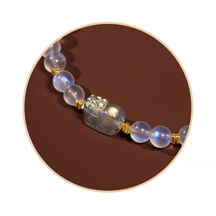 Mondstein Pixiu Armband mit goldenen Perlen auf braunem Hintergrund.