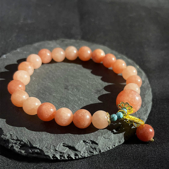 Pfirsichfarbenes Perlenarmband mit Türkis-Anhänger auf Schieferstein.