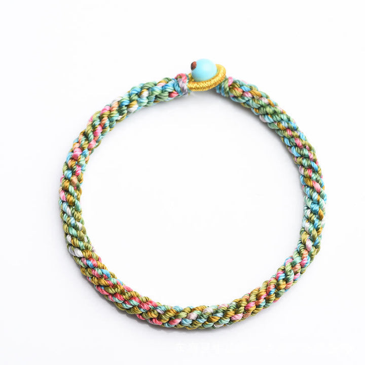 Buntes geflochtenes Armband mit Glücksperle auf weißem Hintergrund.