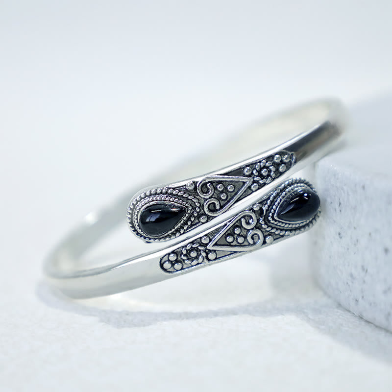 Silbernes Armband mit schwarzen Steinen Boho-Stil auf weißem Stein