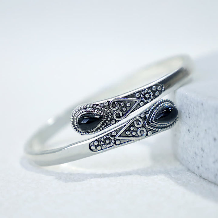 Silbernes Armband mit schwarzen Steinen Boho-Stil auf weißem Stein