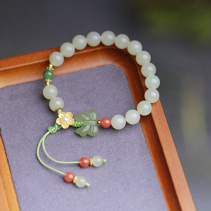 Jade Armband mit Schmetterling, weißen Perlen und roten Akzenten elegant präsentiert.