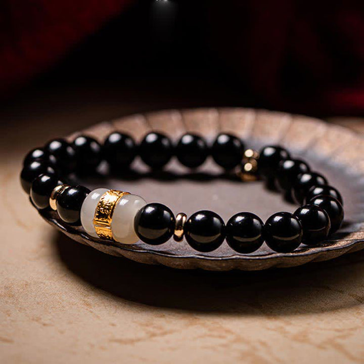 Schwarzes Obsidian Armband mit Jade und goldener Verzierung elegant präsentiert.