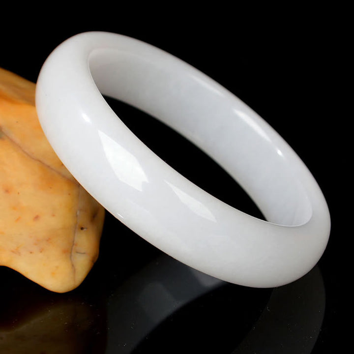 Weißes Jade Armband am Finger eleganter Naturstein glänzend poliert