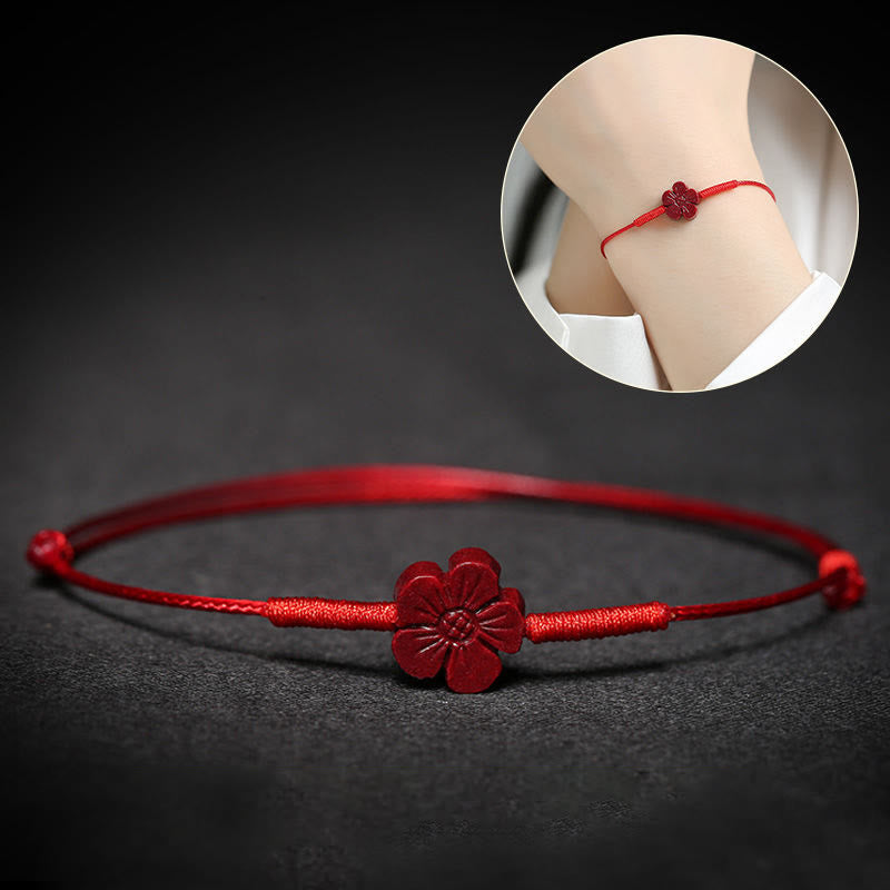 Rotes Armband mit Blütenanhänger am Handgelenk getragen, elastisch
