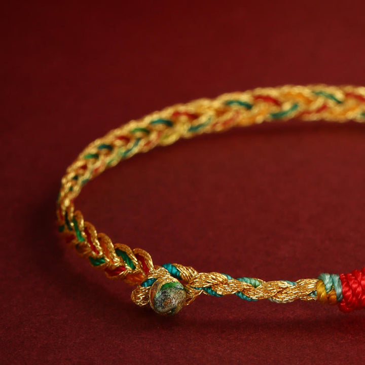 Goldenes Drachen-Armband mit grünen und roten Fäden elastisch getragen