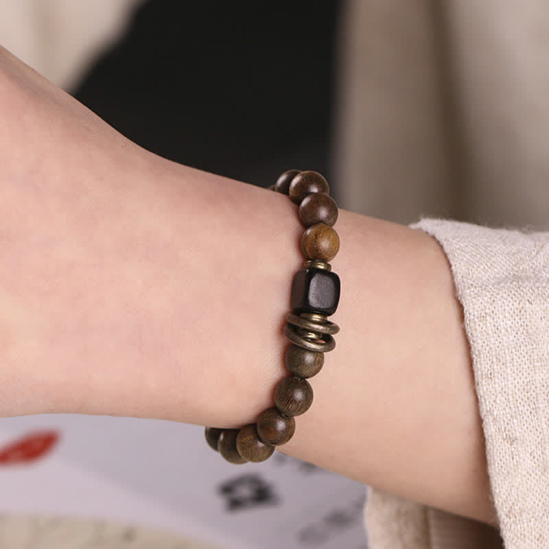 Armband Sandelholz Kristall – Frieden am Handgelenk mit braunen Perlen getragen