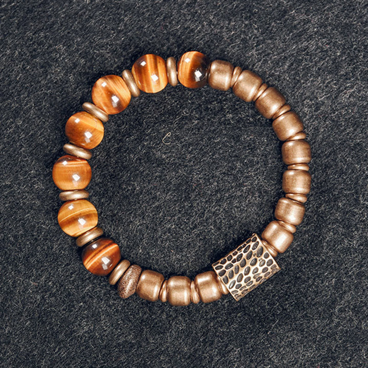 Armband Tigerauge Kupfer mit glänzenden Natursteinen auf grauem Hintergrund