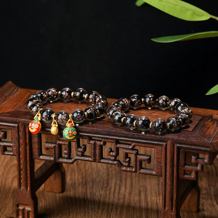 Schwarze Obsidian Perlen Armband mit goldenen Verzierungen elegant präsentiert.