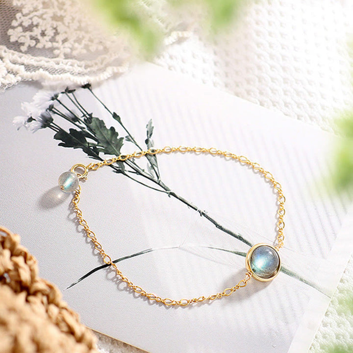 Goldenes Armband Mondstein Mond mit weißen Blüten elegant präsentiert.