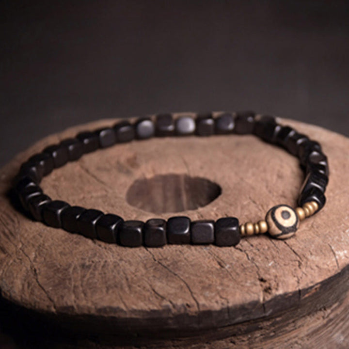 Schwarzes Ebenholz Armband mit Kupfer Perlen auf Holzoberfläche.