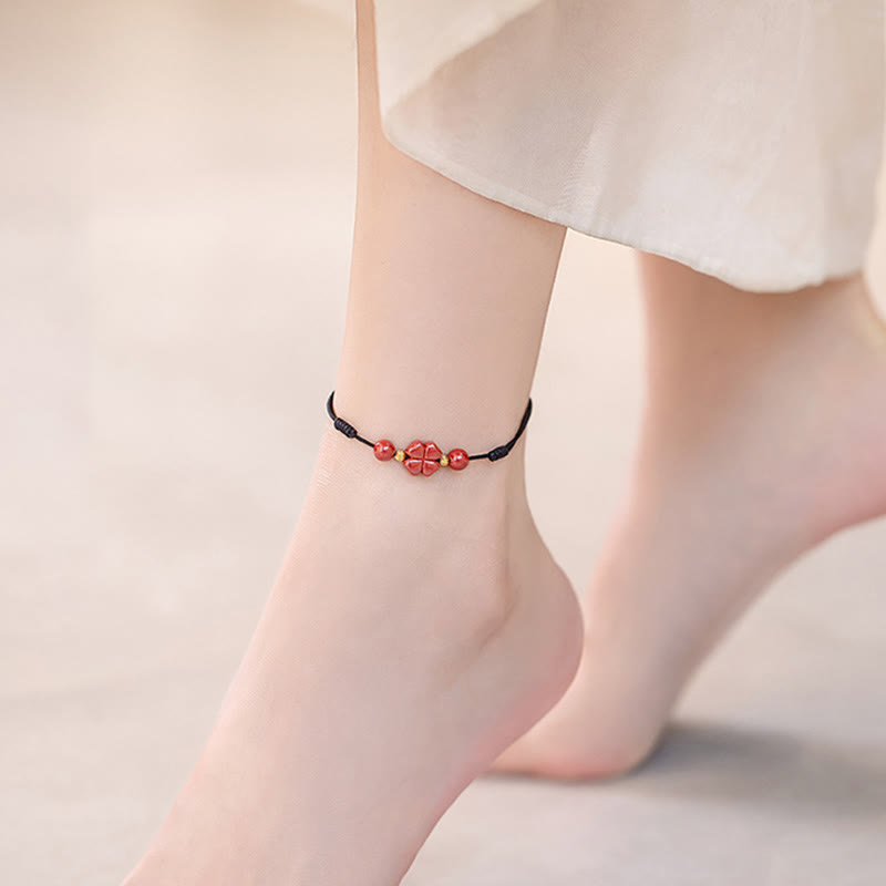 Rotes Armband Zinnober Kleeblatt am Fußgelenk getragen schwarzes Band Liebe Segen