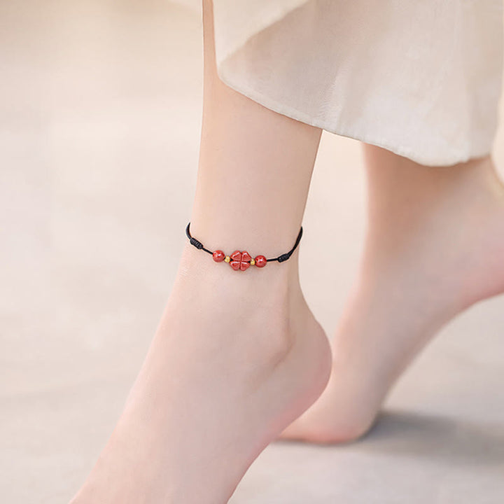 Rotes Armband Zinnober Kleeblatt am Fußgelenk getragen schwarzes Band Liebe Segen