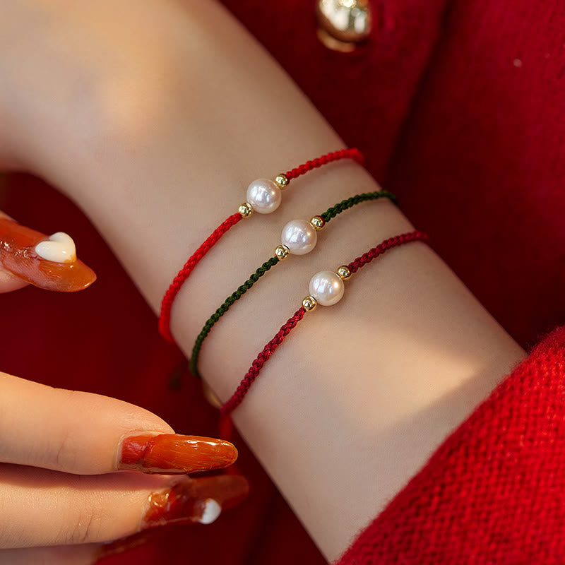 Drei geflochtene Armbänder mit Naturperlen am Handgelenk getragen, rot grün.