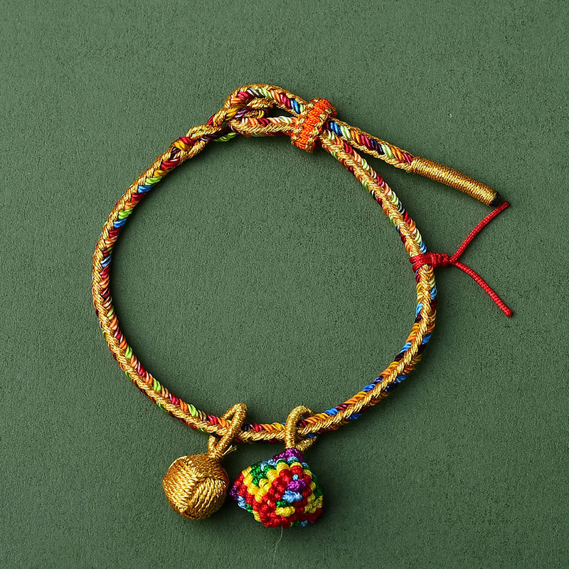 Buntes Glück Armband mit goldenen Perlen auf grünem Hintergrund.