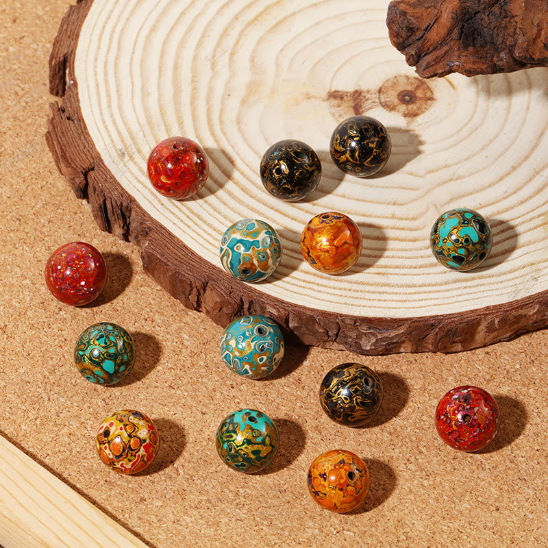 Bunte Lackperlen Armband auf Sand mit Zen Garten Dekoration.