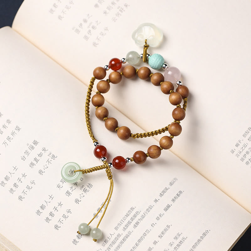 Armband Sandelholz mit bunten Steinen auf offenen Buchseiten.