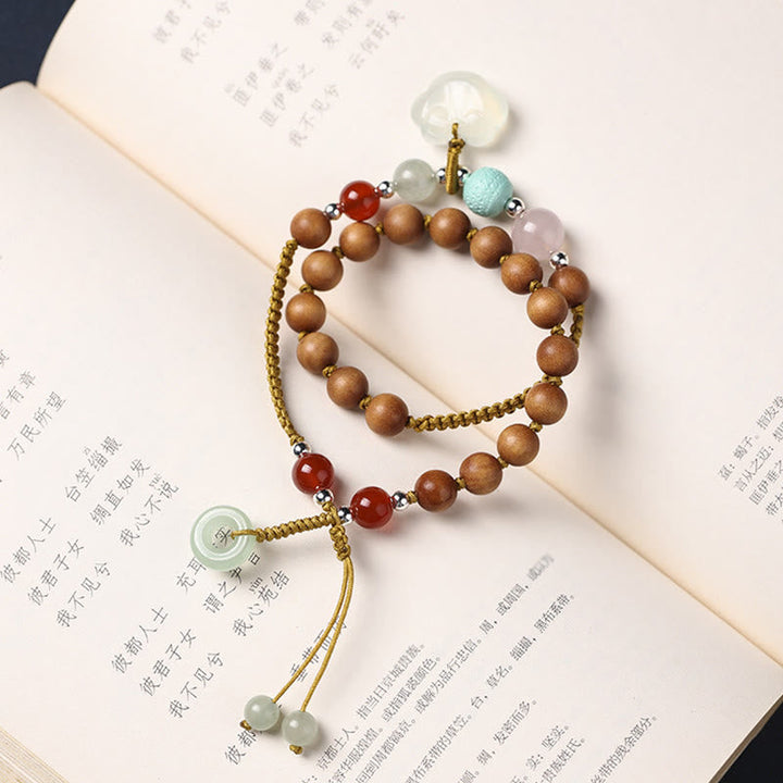 Armband Sandelholz mit bunten Steinen auf offenen Buchseiten.