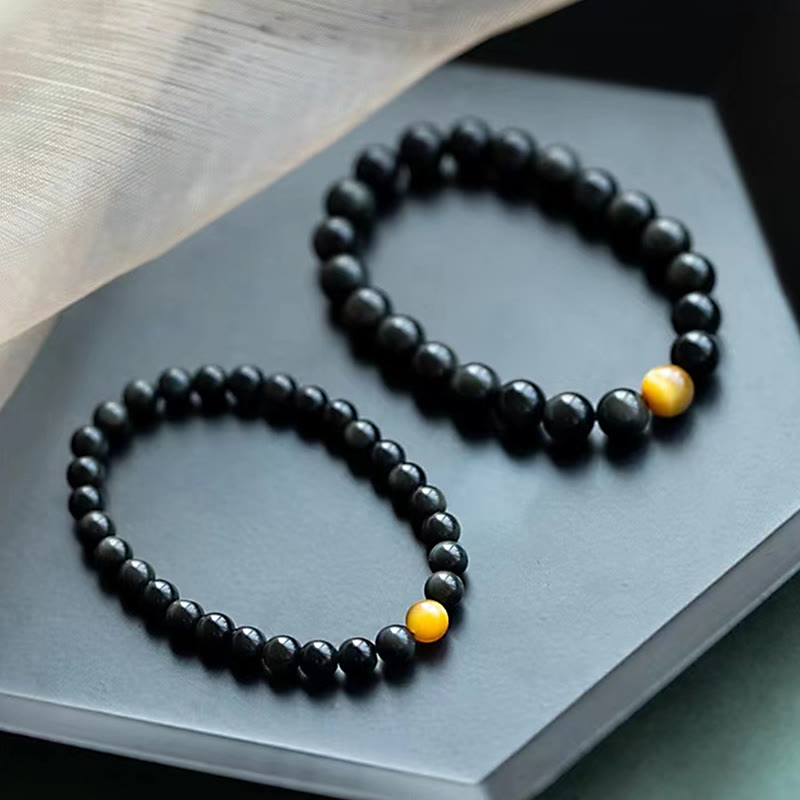 Zwei schwarze Obsidian Armbänder mit goldenem Tigerauge Stein.