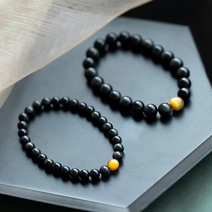 Zwei schwarze Obsidian Armbänder mit goldenem Tigerauge Stein.