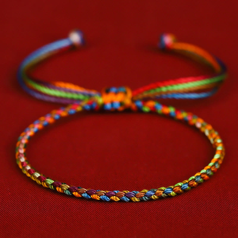 Buntes Armband "Glück" mit Regenbogenfarben auf rotem Hintergrund, Makroaufnahme