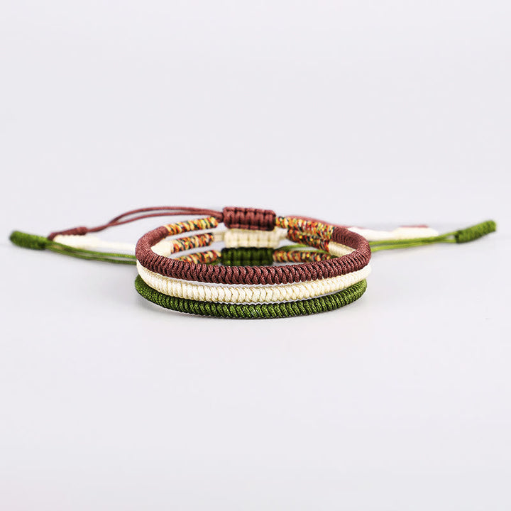 Drei bunte tibetische Armbänder nebeneinander auf weißem Hintergrund angeordnet
