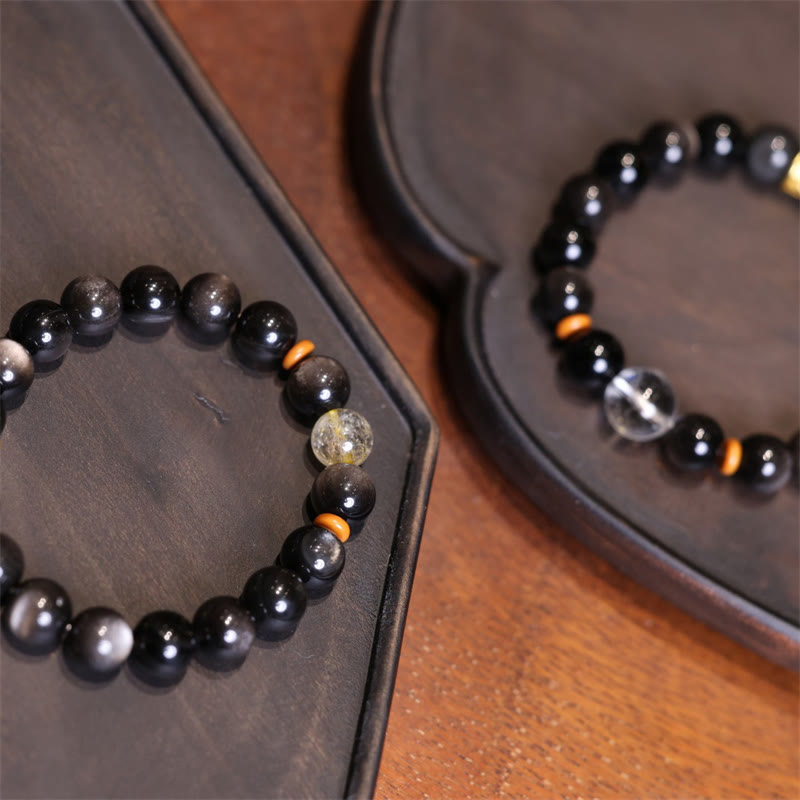 Schwarze Obsidian Kristall Armband mit orangefarbenen Perlen Dekoration.
