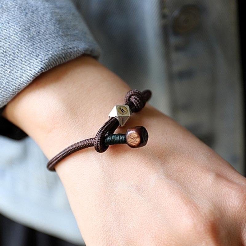 Braunes Armband mit Silber Tierkreis Charm am Handgelenk getragen elegant