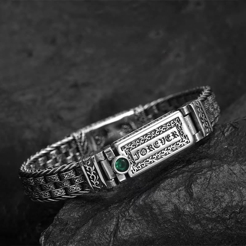 Silbernes Armband mit grünem Stein auf Felsen elegant gestylt.