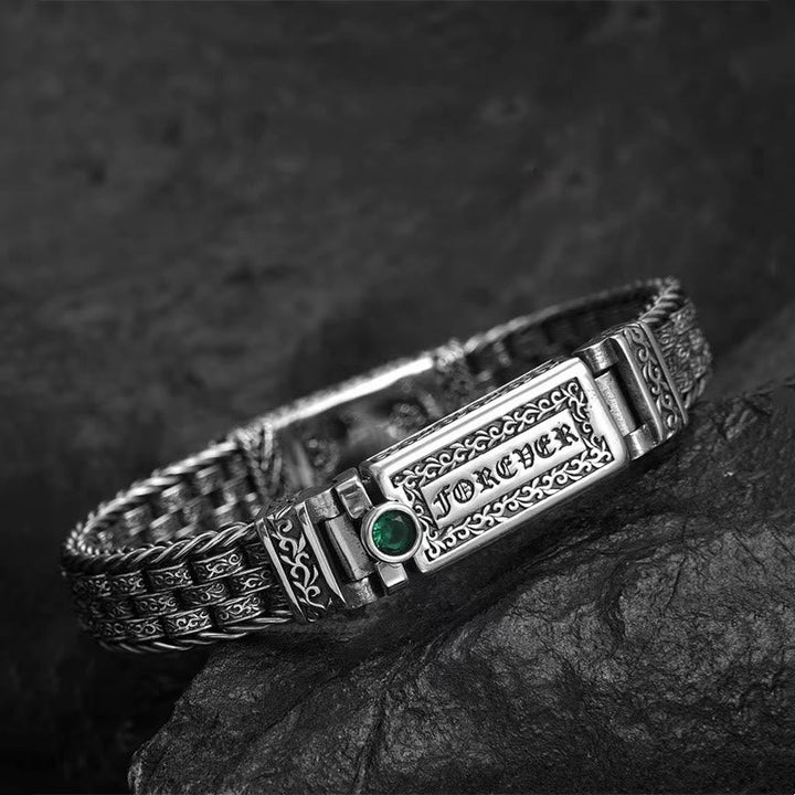 Silbernes Armband mit grünem Stein auf Felsen elegant gestylt.