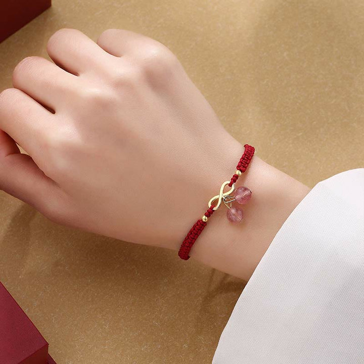 Rotes Armband mit Erdbeerquarz Kristall und Infinity Charm elegant am Handgelenk.