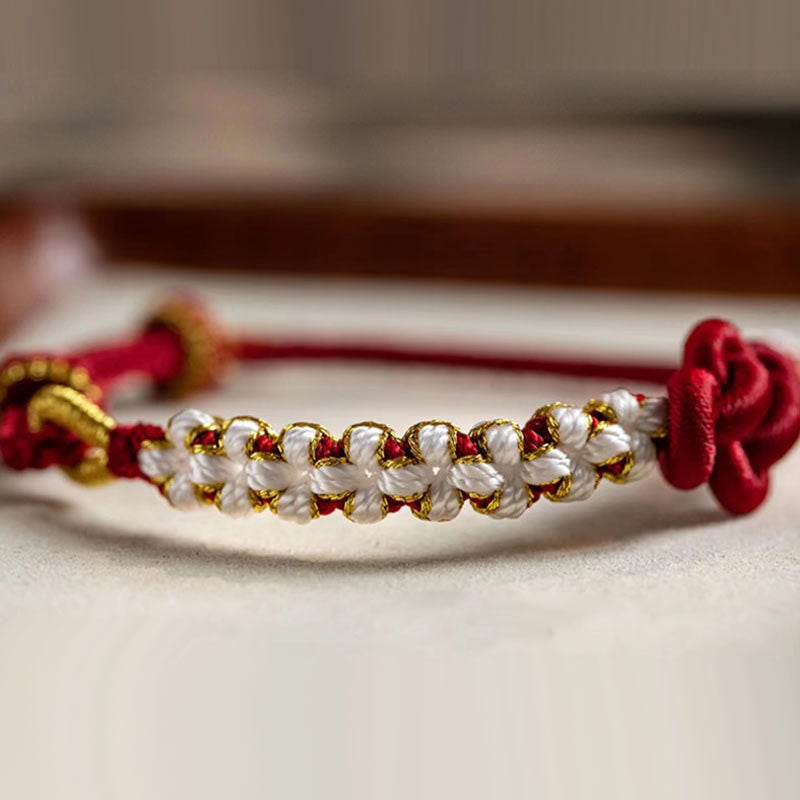 Armband Pfirsichblüte mit Perlen und roten Seidenschleifen elegant.