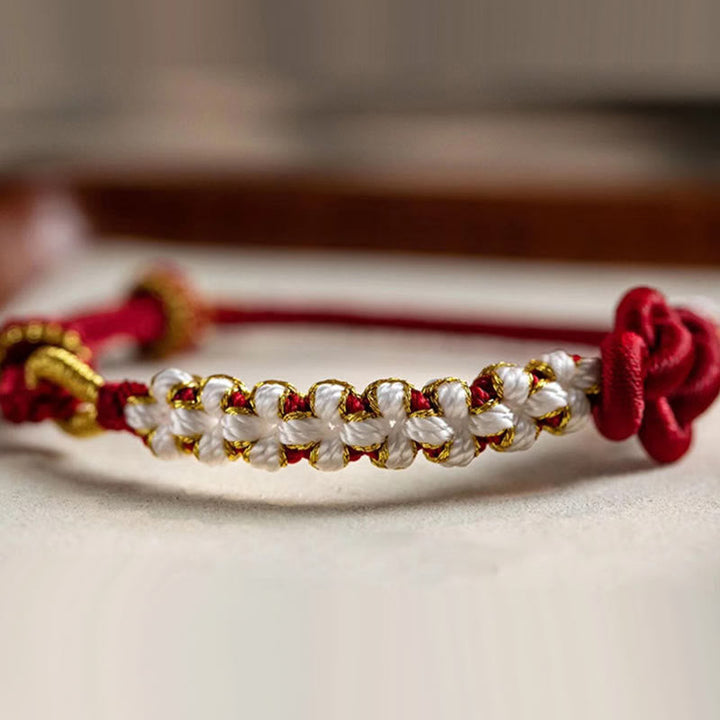 Armband Pfirsichblüte mit Perlen und roten Seidenschleifen elegant.