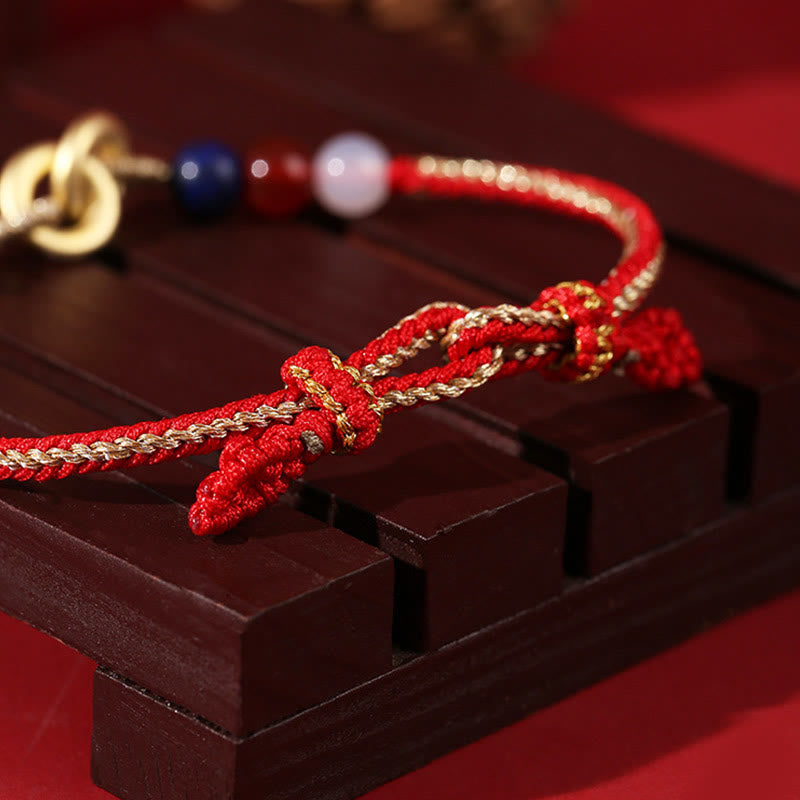 Rotes Armband mit Lotus-Charm und bunten Perlen auf Holz.