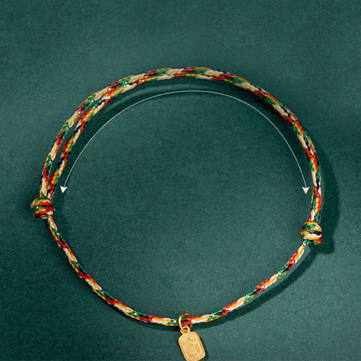 Farbiges Glück Armband Fu-Zeichen mit Gold Anhänger grünem Hintergrund.