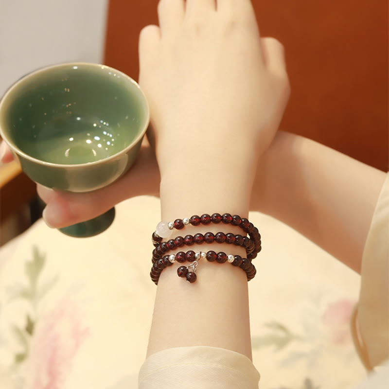 Granit Armband mehrschichtig am Handgelenk mit grüner Teetasse getragen.