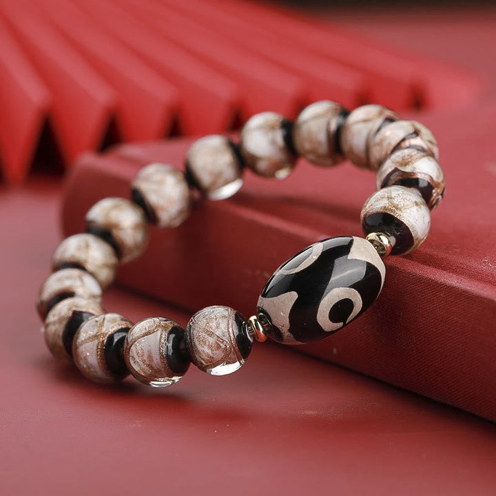 Armband – Wohlstand Balance mit braunen Perlen und schwarzem Amulett elegant.