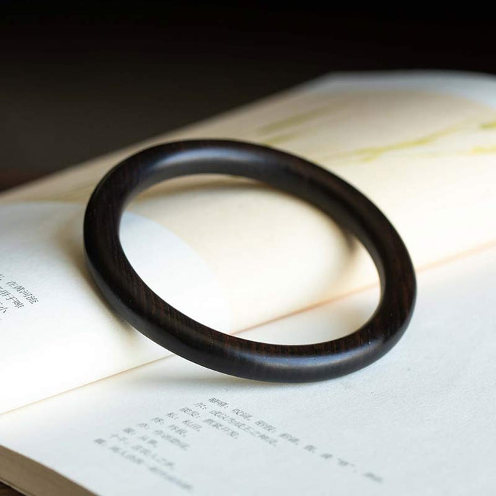 Schwarzes Ebenholz Armband auf aufgeschlagenem Buch Schutz flach
