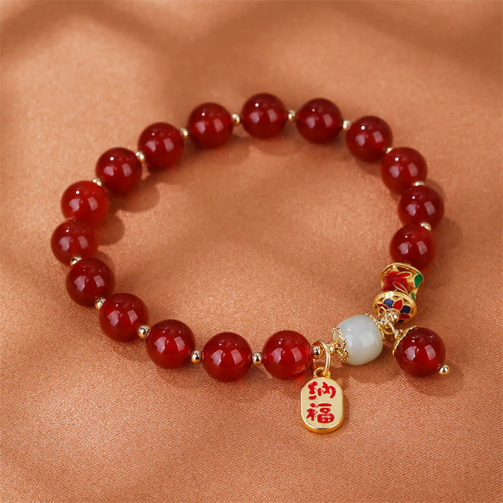 Armband Roter Achat Jade mit goldenem Segenanhänger am Handgelenk