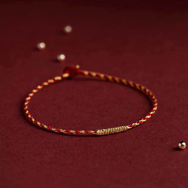 Rotes goldenes geflochtenes Armband mit Knoten auf burgunderfarbenem Hintergrund