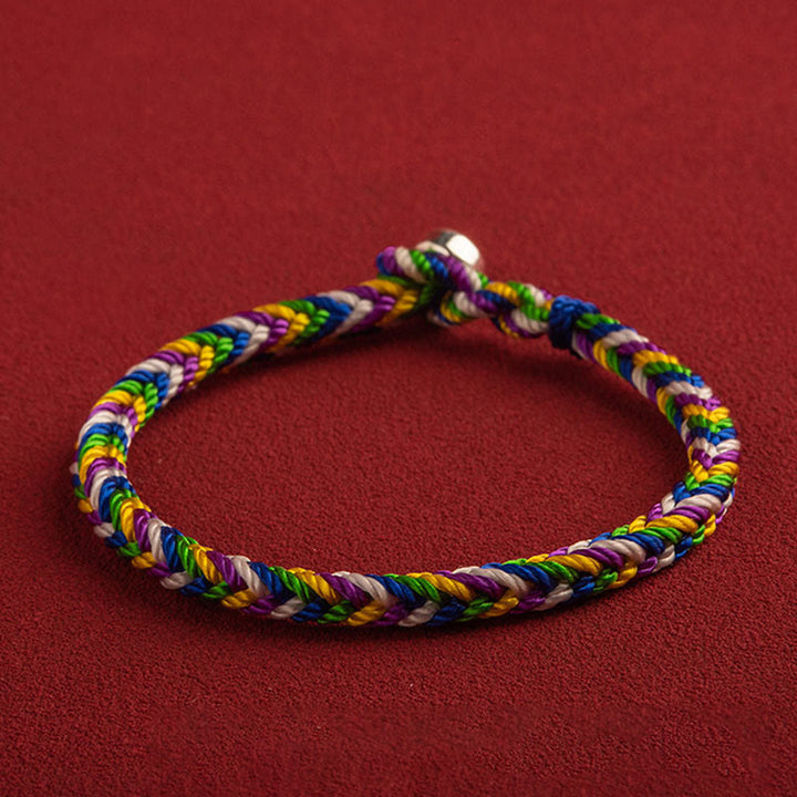 Buntes Glücks-Armband mit geflochtenen Fäden am Handgelenk getragen.