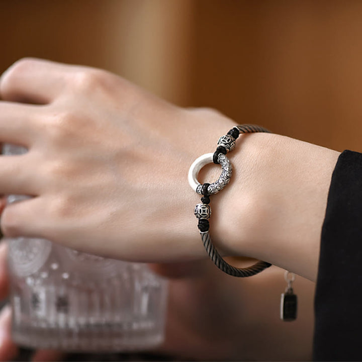 Silbernes Armband mit Kupfer Fu-Zeichen am Handgelenk einer Frau getragen.