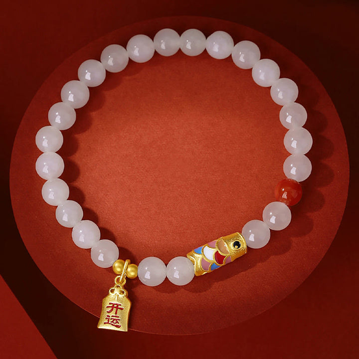 Weiße Jade Armband mit goldener Koi Fisch Anhänger auf rot.