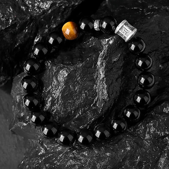 Schwarzes Obsidian Armband mit goldenem Akzent auf Steinoberfläche